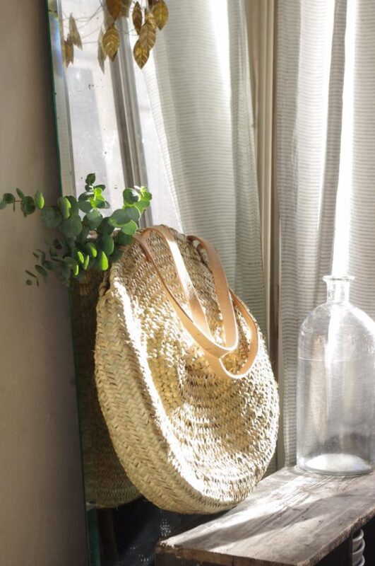 Round French basket on a sunny windowsill beside a glass jug
