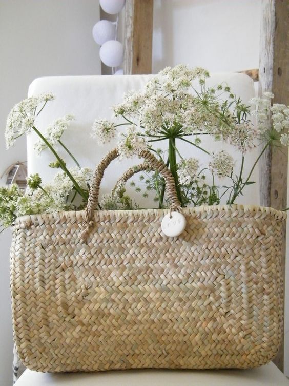 Rectangular French market basket filled with white flowers on a linen-covered chair