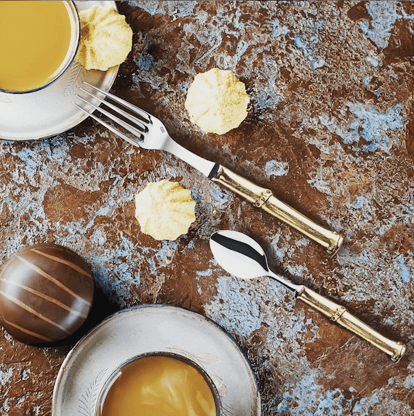 Elegant André Verdier cutlery with gold handles styled alongside coffee and sweets