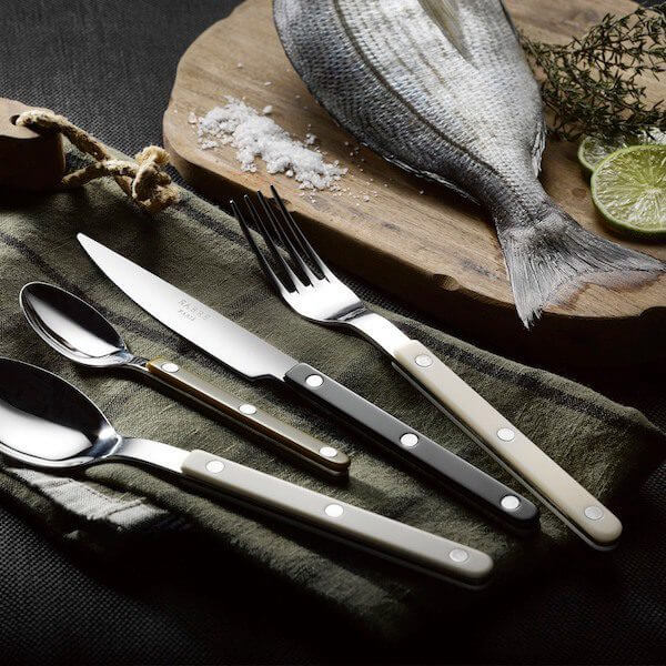Elegant Sabre Paris cutlery set displayed beside fresh fish and herbs on a rustic table