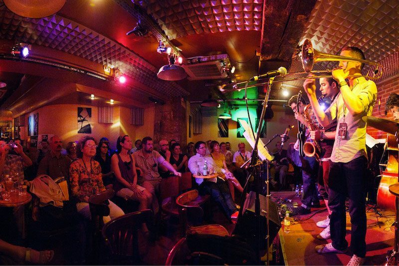 Moody blue-lit interior of Sunset/Sunside jazz club where acoustic and electric sets collide